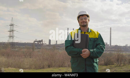 Die männlichen Ingenieur Projekte die Arbeit. Sonne und Wolken. Der Mann befindet sich in einer grünen sunglass Weste gekleidet Stockfoto