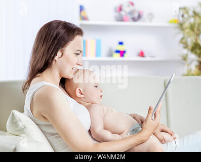 Glückliche Mutter ein Jahr altes Baby Holding auf seinen Händen und zeigt ihr Bild auf digital Tablet Stockfoto
