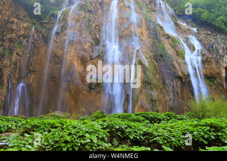 Einem malerischen Wasserfall unter großen Steinen in der Plitvicer Seen, Kroatien im Frühjahr oder Sommer. Kroatische Wasserfälle, Berge und Natur Stockfoto