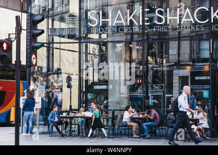 London, Großbritannien - 15 Juli, 2019: die Menschen an den Tischen im Freien von Shake Shack in Victoria Station sitzen. Shake Shack ist eine US-amerikanische Fast-Food-Restaurant c Stockfoto