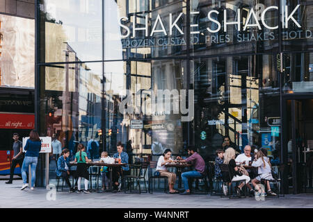 London, Großbritannien - 15 Juli, 2019: die Menschen an den Tischen im Freien von Shake Shack in Victoria Station sitzen. Shake Shack ist eine US-amerikanische Fast-Food-Restaurant c Stockfoto