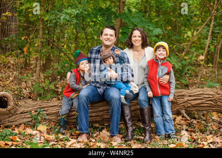 Eine lächelnde Familie sitzen zusammen auf einem im Wald anmelden Stockfoto