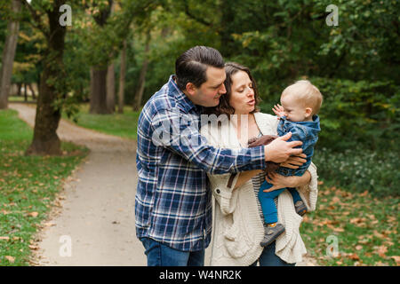 Eine Mutter und Vater zärtlich halten Sie Ihr kleines Kind in ihre Arme Stockfoto