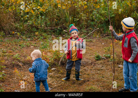 Drei kleine Jungen spielen zusammen in einer Wiese im Herbst Stockfoto