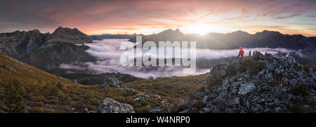 Mann beobachten Nebeln bei Sonnenaufgang vom Gipfel der Berge Stockfoto