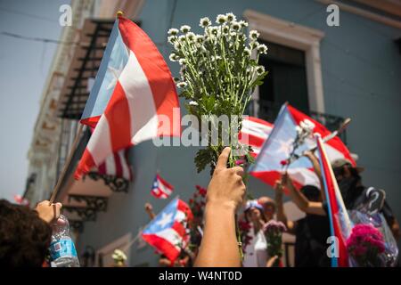 San Juan, Puerto Rico. 24. Juli, 2019. Demonstranten protestieren mit Puerto Rican Fahnen und Blumen vor der Residenz des Gouverneurs Rossello, auch bekannt als La Fortaleza. Die Proteste von einem Korruptionsskandal in der Regierung und die Veröffentlichung von Nachrichten in einer Chat Group, in denen ausgelöst wurden, entsprechend viele, einige Bemerkungen waren feindselig gegenüber Frauen und Homosexuellen und respektlos der zahlreichen Opfer des Hurrikan Maria von 2017. Puerto Rico's Kopf der Regierung, Rossello, ist immer noch im Amt, im Gegensatz zu den anhaltenden Spekulationen über seinen Rücktritt. Credit: Marcos Caballero/dpa/Alamy leben Nachrichten Stockfoto