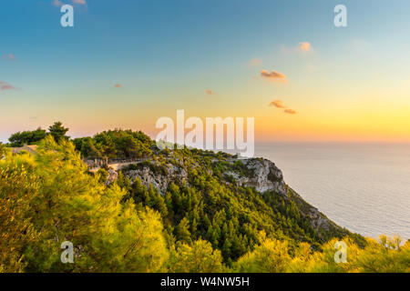 Griechenland, Zakynthos, endlosen Ozean Horizont hinter grünen Klippe in den romantischen Sonnenuntergang Licht Stockfoto