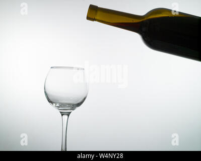 Rotwein füllt ein leeres Glas Wein auf weißem Hintergrund Stockfoto