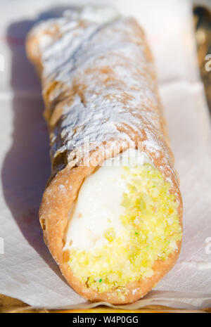 Sizilianischem cannolo - ein süßes Gebäck mit Ricotta Frischkäse gefüllt und mit Puderzucker - sitzen warten auf eine Serviette, gegessen zu werden beschichtet. Stockfoto