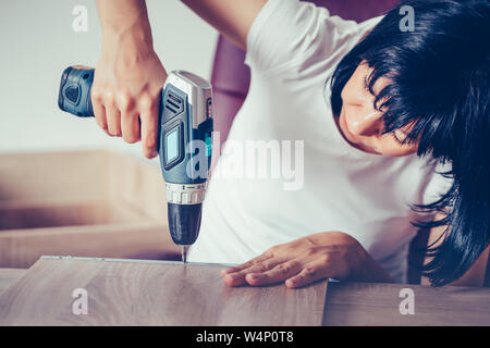 Close up Portrait von unabhängigen Frau mit einem Akkuschrauber Montage neuer Möbel in Ihrem Haus. Stockfoto