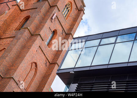 Alte Architektur Neben moderner Architektur mit alten gotischen Turm und moderne Gebäude aus Glas. Stockfoto