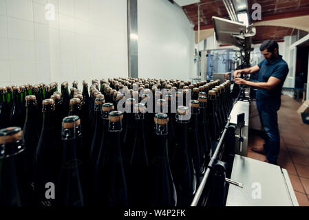 Seitenansicht des Menschen prüfen Korken in der Flasche Cava Alkohol bei der Herstellung Weinkeller im Penedes region, Katalonien, Spanien Stockfoto