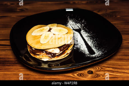 Stapel Pfannkuchen mit Bananenscheiben und Schokolade Sirup Stockfoto