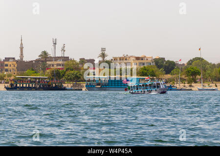 Luxor, Ägypten - 16. April 2019: Touristische riverboats mit nationalen Flaggen Kreuzfahrt auf dem Nil in Luxor, Ägypten Stockfoto