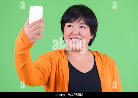 Junge glücklich Übergewicht asiatische Frau unter selfie bereit für Fitnessraum Stockfoto