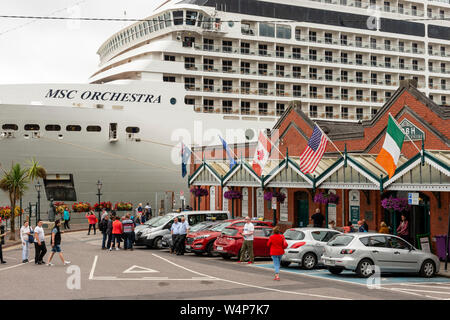 Das MSC Orchestra Kreuzfahrtschiff dominiert die Aussicht, da es am Kreuzfahrtanleger und dem Cobh Heritage Centre, Cobh, County Cork, Irland als 2019 anlegt Stockfoto