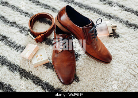 Für den Bräutigam Hochzeit Zubehör. Aus braunem Leder, Schuhe, Gürtel, Parfum, goldene Ringe in Box. Männliche Mode Stockfoto