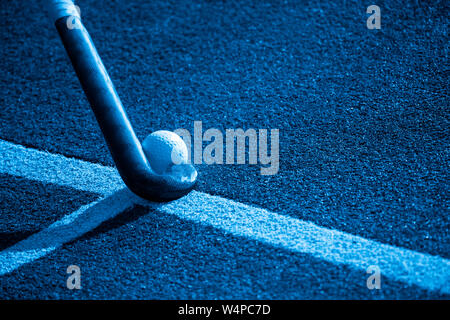 Hockey Stick und Ball auf gefälschtes Gras mit Platz kopieren. Filter Blau. Stockfoto