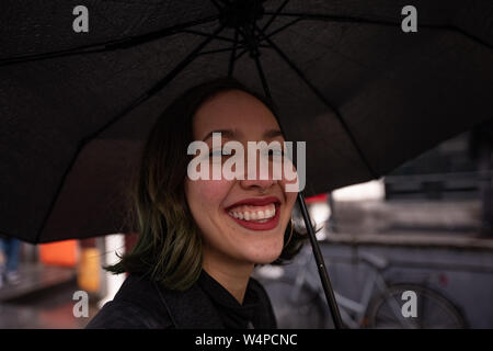 Lächelnden jungen Frau unter dem Dach wandern in rainny Tag. Stockfoto
