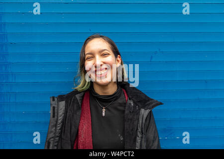 Glückliche Frau stehen im Regen auf der Straße, in der Nähe der blauen Wand. Stockfoto