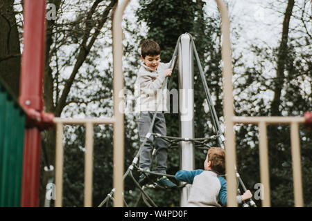 Zwei Jungen spielen auf klettergerüst am Spielplatz Stockfoto