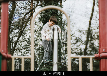 Seitenansicht der Junge oben am Klettergerüst am Spielplatz Stockfoto