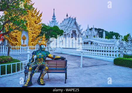 CHIANG RAI, THAILAND - 9. Mai 2019: Thai Stil Roboter sitzt auf der Bank vor der Abend weiße Tempel (Wat Rongkhun), am 9. Mai in Chiang Rai Stockfoto