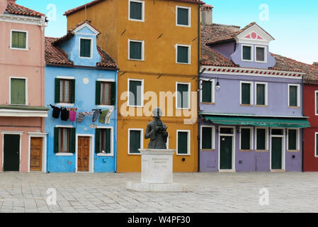 Burano, Italien - Januar 10, 2017; die Statue des Venezianischen Komponisten Baldassare Galuppi auf dem Hauptplatz der Insel Burano mit berühmten retro Häuser Stockfoto