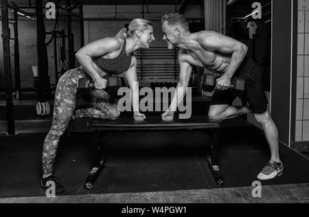 Einen mittleren Alters attraktiv und sportlich Paar zusammen tut ein funktionelles Fitness Training und Spaß haben. Mann und Frau sind das Lachen in der Turnhalle. Stockfoto