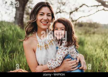 Portrait von Mutter und Tochter in hintergrundbeleuchtete Feld lächelnd an Kamera Stockfoto