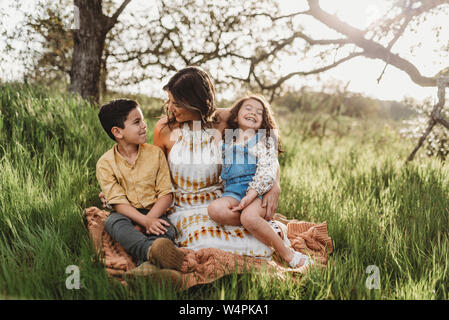 Mutter, Sohn und Tochter in hintergrundbeleuchtete Feld an jedem anderen lächelnd Stockfoto