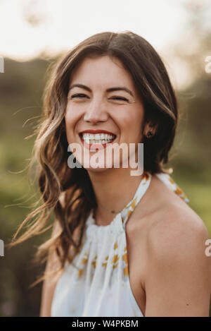 Headshot junge brünette Frauen lächelnd in Feld mit Hintergrundbeleuchtung Stockfoto