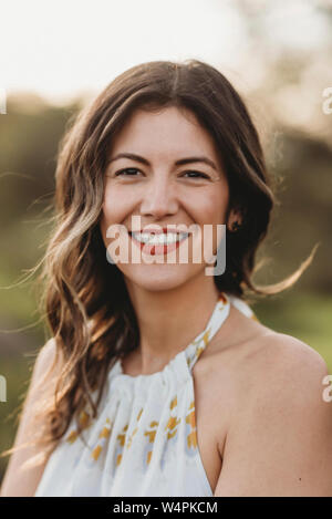 Headshot junge brünette Frauen lächelnd in Feld mit Hintergrundbeleuchtung Stockfoto