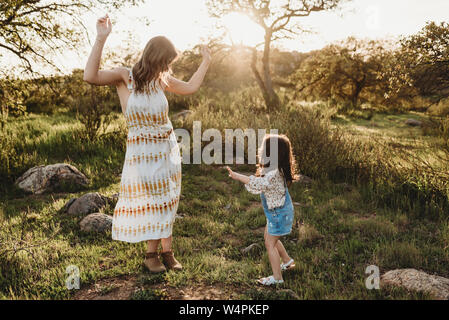 Junge Mutter und Tochter tanzen im Sonnenlicht im hellen Bereich Stockfoto