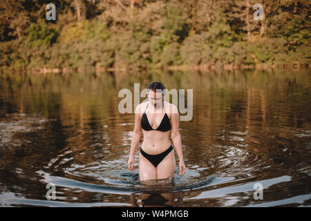 Junge Frau im Bikini walking im Fluss Stockfoto