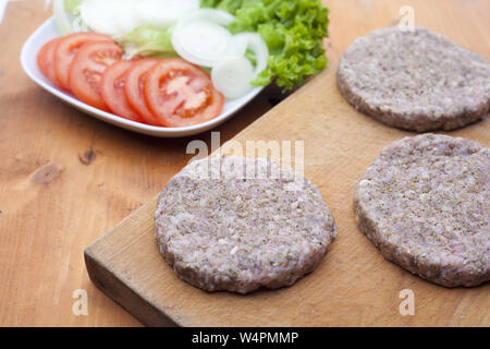 Rohes Rindfleisch Burger gegen Weiße auf Küche Schneidbrett Stockfoto