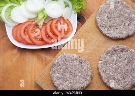 Rohes Rindfleisch Burger gegen Weiße auf Küche Schneidbrett Stockfoto