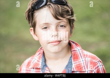 Junge, 10 Jahre alt, mit Sonnenbrille und Plaid Shirt sieht cool aus in die Kamera, Porträt, Deutschland Stockfoto