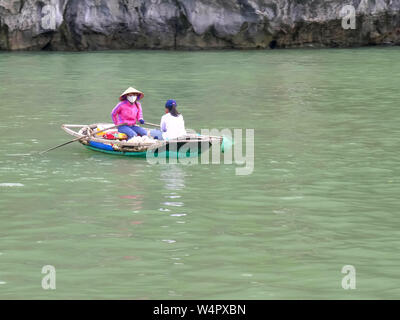 Zwei Frauen in einem kleinen Boot sammeln Müll von Halong Bay Stockfoto