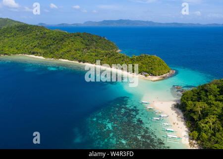 Luftbild von Auslegerbooten, die am Strand festgemacht sind Paradise Island, Port Barton, Palawan, Philippinen. Die Insel auf der linken Seite, almos Stockfoto