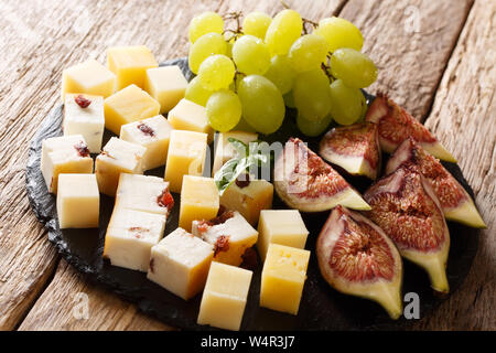 Mediterrane Vorspeisen Vorspeisen, Käse, frische Weintrauben und Feigen close-up auf einer Schiefertafel Board auf dem Tisch. Horizontale Stockfoto