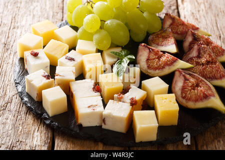 Snacks von Käse, frische Weintrauben und Feigen close-up auf einer Schiefertafel Board auf dem Tisch. Horizontale Stockfoto