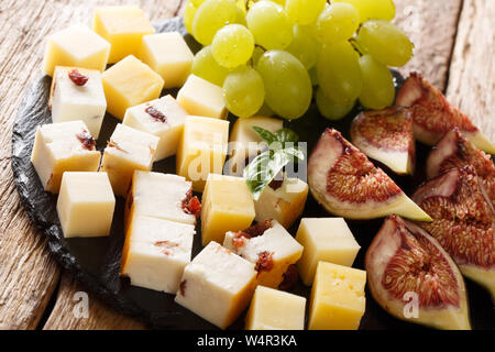 Köstliche französische Käse, Weintrauben und Feigen close-up auf einer Schiefertafel Board auf dem Tisch. Horizontale Stockfoto