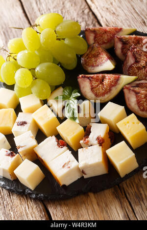 Leckere Antipasti Appetithappen von verschiedenen Käse, Weintrauben und Feigen close-up auf einer Schiefertafel Board auf dem Tisch. Vertikale Stockfoto