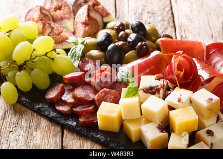 Mediterraner snack Schale mit Käse, Schinken, Trauben, Feigen, Oliven, Würste und close-up auf einem Holztisch. Horizontale Stockfoto