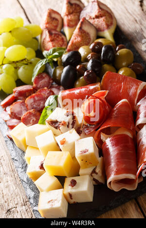 Italienische Antipasti aus Käse, Schinken, Trauben, Feigen, Oliven, Würste und close-up auf einem Holztisch. Vertikale Stockfoto