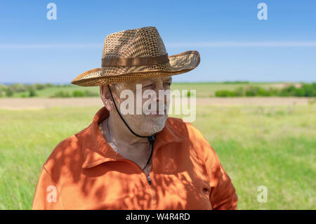 Portrait von bärtigen Kaukasischen senior Bauer gegen grünen landwirtschaftlichen Bereich und in die Zukunft Stockfoto