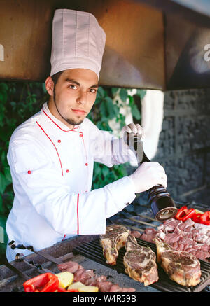 Der Küchenchef bereitet das Fleisch auf dem Grill. Stockfoto