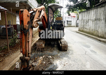 ANTIPOLO CITY, Philippinen - Juli 23, 2019: Ein Bagger ist an der Seite der Straße nach einem Tag an einer Straße Baustelle geparkt. Stockfoto