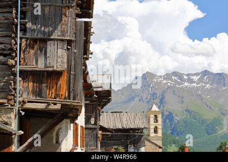 Traditionelle Holzhäuser und die Kirche in Saint Veran, mit der Bergkette im Hintergrund, im Regionalen Naturpark Queyras, Südliche Alpen, Frankreich Stockfoto